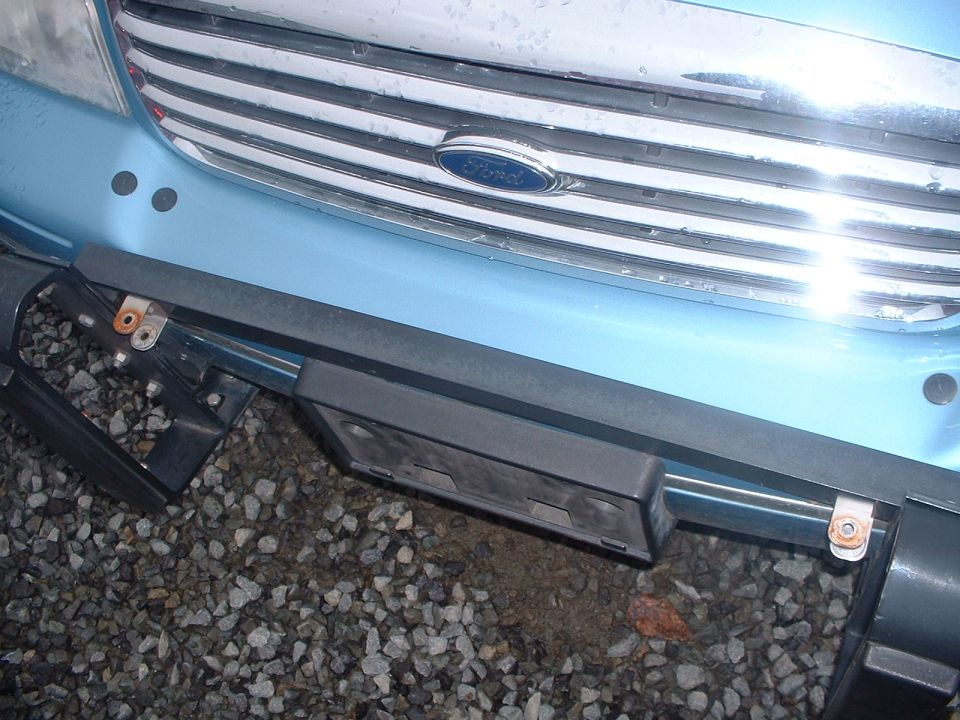 Front of a light blue Ford with a chrome grille and license plate bracket