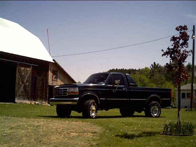 Dark blue Ford F-Series truck parked on grass next to a barn