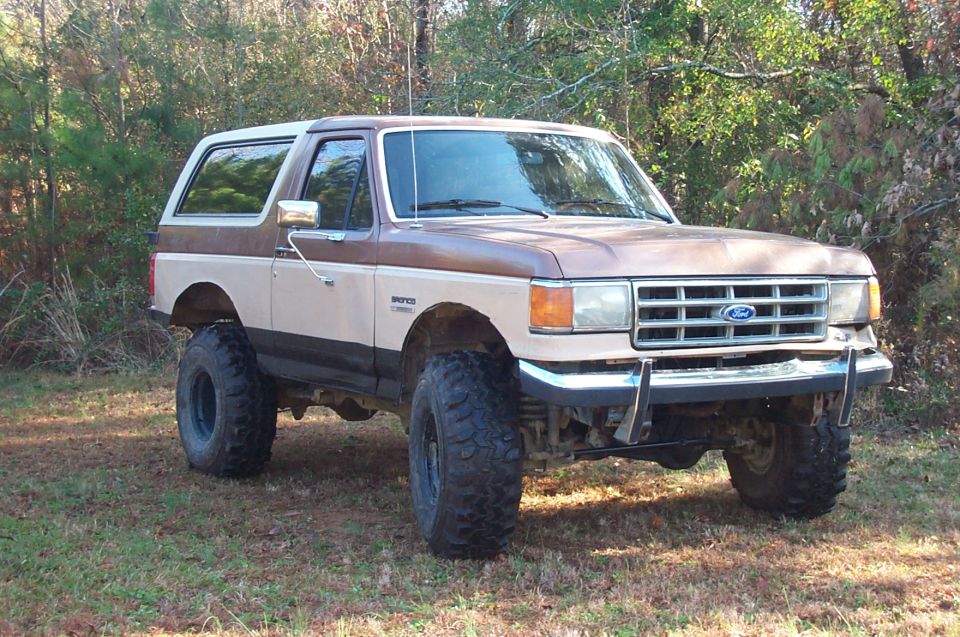 Brown and tan lifted 1987 Ford Bronco parked outdoors