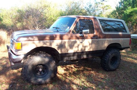 1987 Ford Bronco - This lifted Ford Bronco is shown from the side, highlighting its off-road modifications.
