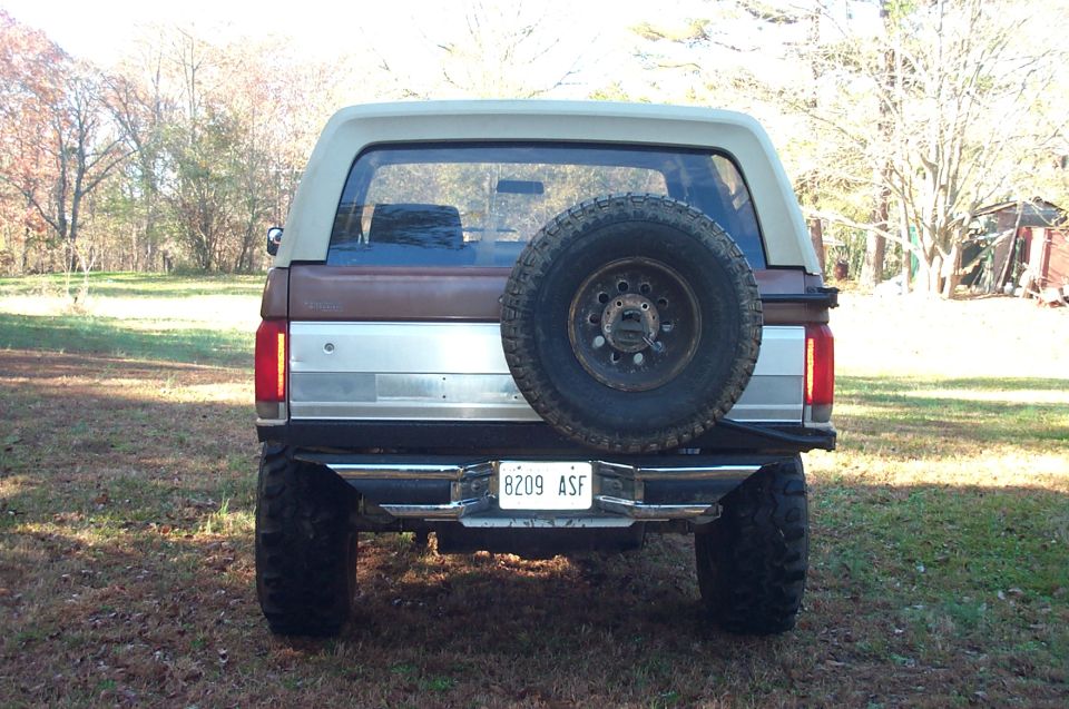 Brown and tan Ford Bronco rear view with spare tire mounted on the back. License plate reads 8209 ASF