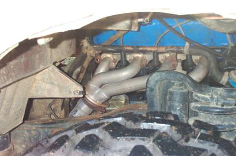 1987 Ford Bronco - Close-up of engine components, including silver headers and a blue valve cover.