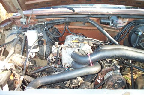 1987 Ford Bronco - Engine bay view showing headers and air conditioning components. The year is not discernible from the image.