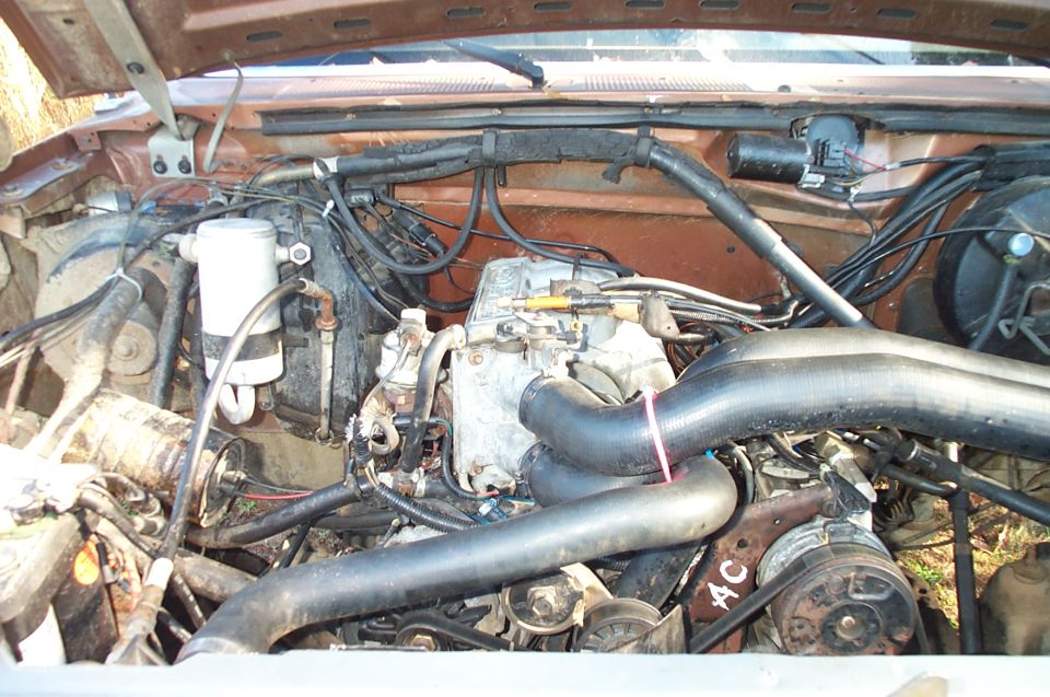 Engine bay with headers and visible 'AC' marking
