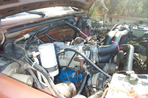 1987 Ford Bronco - The engine bay of a vehicle, showing various mechanical parts and wiring.