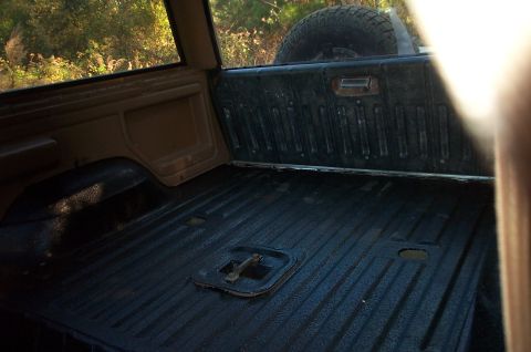 1987 Ford Bronco - The cargo area of the SUV shows a textured floor and a spare tire mounted at the rear.