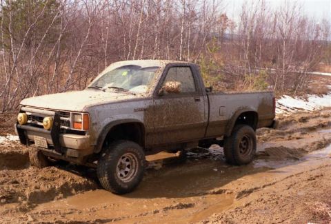 1991 Ford Bronco - This pickup truck is stuck in a muddy off-road trail, its tires struggling for traction.