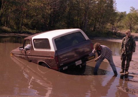 1991 Ford Bronco - A Ford Bronco is stuck in the mud, with two men attempting to free it.