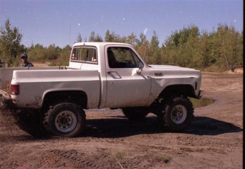 1991 Ford Bronco - This white pickup truck, likely a 1973 model, is shown in profile with large off-road tires, kicking up dirt.