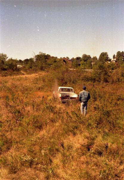 1991 Ford Bronco - Pickup truck navigates off-road terrain with a man observing.