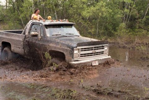 1991 Ford Bronco - This Chevrolet pickup truck is stuck deep in the mud, with a person visible in the cab.