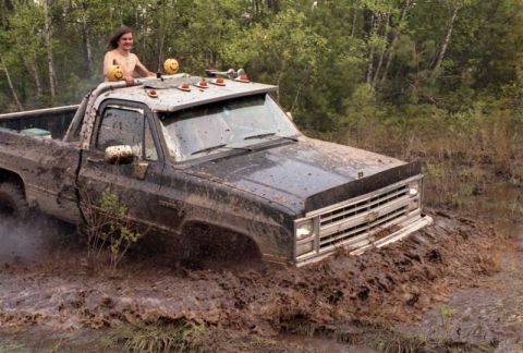 1991 Ford Bronco - This truck is deep in the mud, with a person standing up in the bed.
