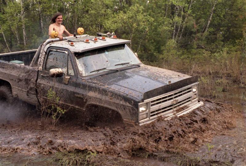 Truck stuck in mud, person standing in the bed