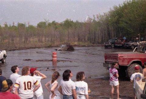 1991 Ford Bronco - A group of spectators watches as several trucks participate in a mud bogging event.