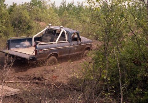 1991 Ford Bronco - This blue pickup truck navigates a muddy trail with its tailgate down.