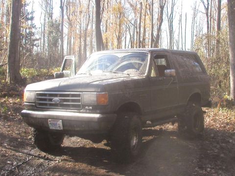 1988 Ford Bronco - This 1988 Ford Bronco is seen off-road with its driver's door ajar, surrounded by trees.