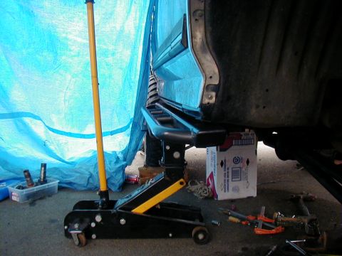 1991 Ford Bronco - The side of a 1991 Ford Bronco is shown with running boards being installed, supported by a jack.