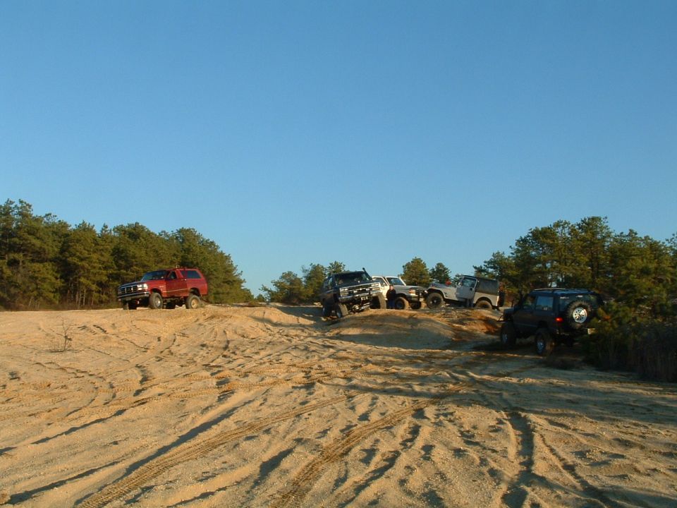Four-door SUV with spare tire on rear, parked on sandy terrain
