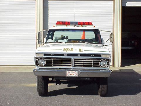 1973 Ford F-250 - This 1973 Ford F-250 fire truck, marked "SQUAD - 111", is seen from the front with its emergency lights on.