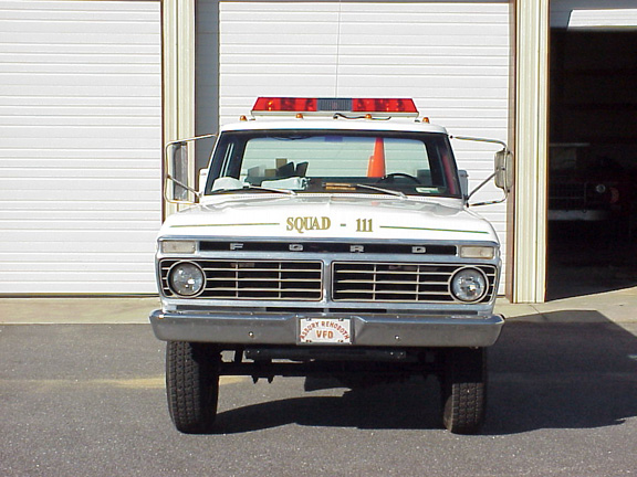 Front view of a 1973 Ford F-250 fire truck with "SQUAD - 111" on the hood