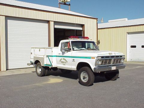 1973 Ford F-250 - White 1973 Ford F-250 utility truck parked in front of a garage bay.