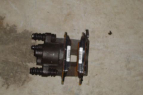 1993 Ford Bronco - A dark-colored brake caliper is shown resting on a concrete surface, two white labels with text.