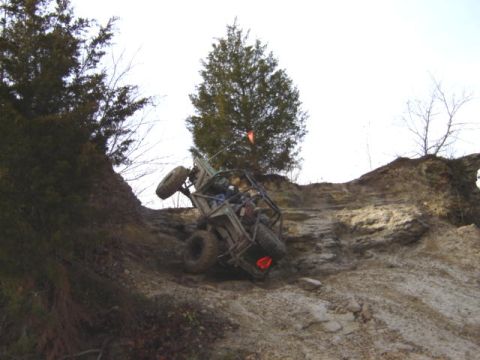 1992 Ford Bronco - An off-road vehicle navigates a challenging, steep, and rocky terrain under a bright sky.