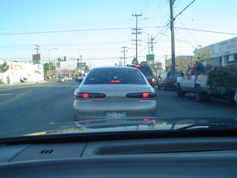 1993 Ford Taurus - A gold sedan is seen from behind in traffic, its brake lights illuminated. The license plate is visible.