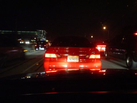 1993 Ford Taurus - A red sedan with license plate 7VZH071 is seen at night on a highway, with other vehicles around.