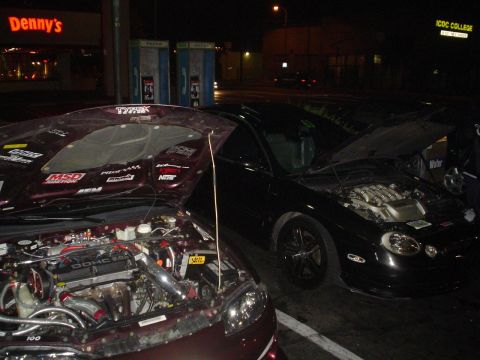 1993 Ford Taurus - Two cars with hoods open at night, one black sedan and one maroon car.
