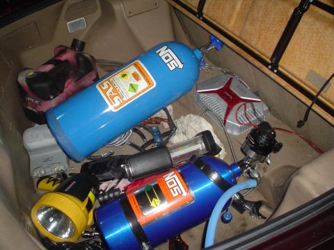 1993 Ford Taurus - The trunk of a car contains two NOS tanks, a flashlight, a fuel can, and an audio amplifier.