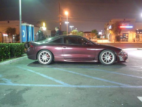 1993 Ford Taurus - A purple coupe is parked in a lot at night, with two people standing near payphones in the background.