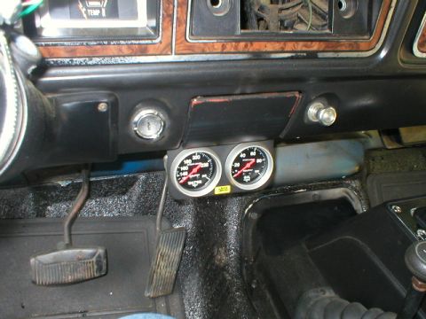 1978 Ford Bronco - Under-dash view of a vintage truck interior showing a black two-gauge pod with aftermarket water temperature and oil pressure gauges mounte…