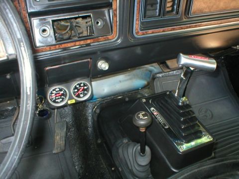 1978 Ford Bronco - Interior console view showing a chrome B&M-style ratchet shifter with red logo, a black floor-mounted transfer case shifter with a knob, an…