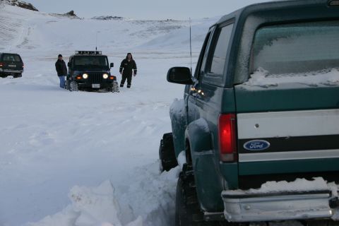 1996 Ford Bronco - A 1996 Ford Bronco is seen from the rear in a snowy landscape, with other vehicles and people nearby.