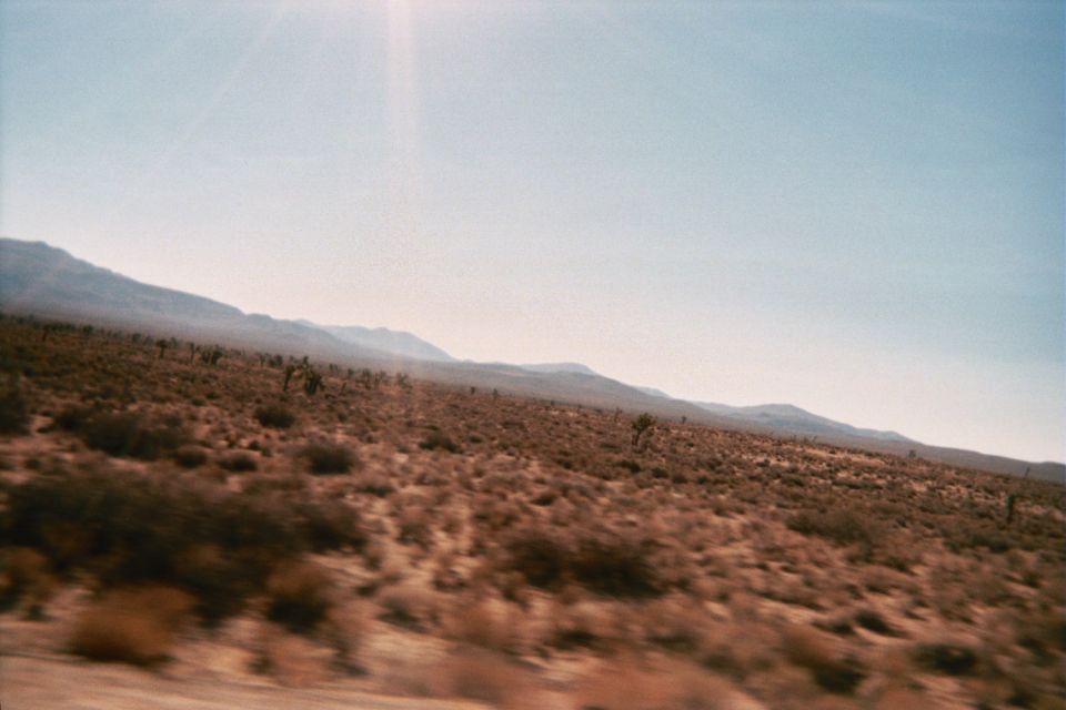 Desert scrubland with distant mountains under a hazy blue sky