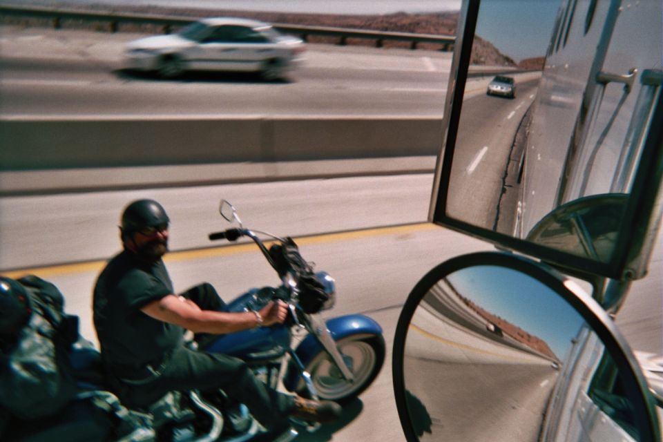 Helmeted motorcyclist on a blue cruiser on a highway, mirror at right