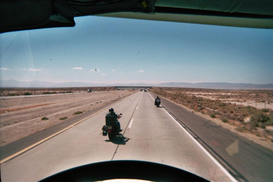 View from behind a motorcycle of two riders on a desert highway