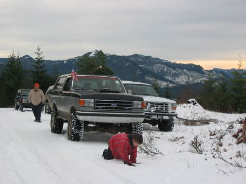 1995 Ford Bronco - A group of Ford Broncos on a snowy mountain road, one carrying a Christmas tree.
