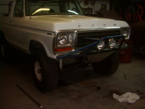 1978 Ford Bronco - The front of a white 1978 Ford Bronco is shown with a custom blue bumper and off-road tires.