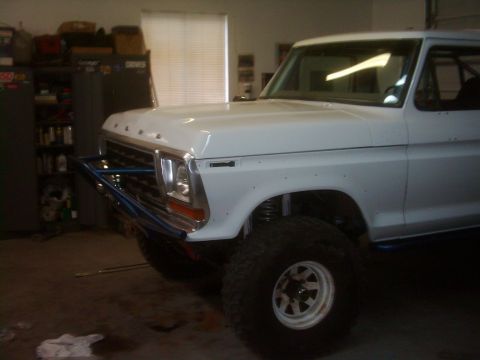 1978 Ford Bronco - White 1978 Ford Bronco in a garage, a custom bumper and lifted suspension.