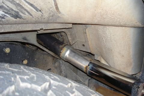 1987 Ford Bronco - A newly installed exhaust pipe is visible on the underside of a vehicle, near the rear tire.