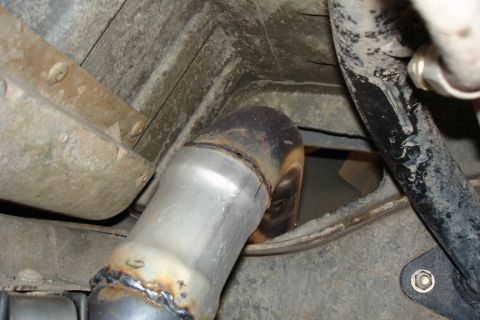 1987 Ford Bronco - A close-up view of a newly welded exhaust pipe section on the underside of a vehicle.