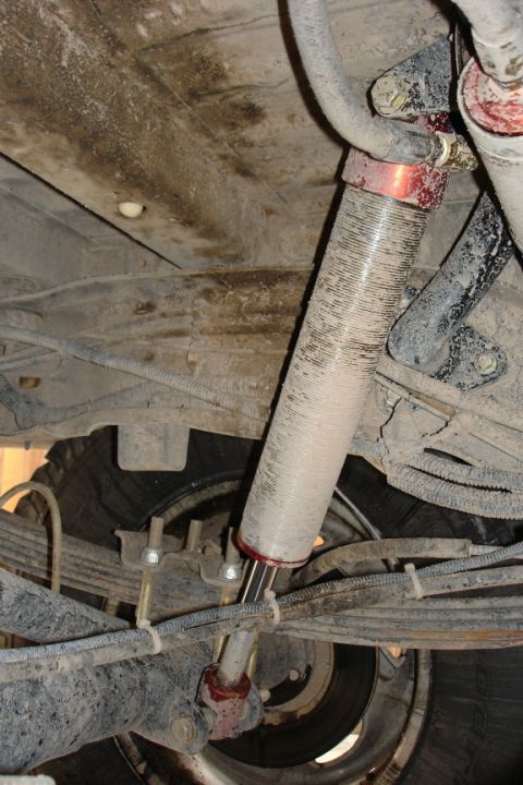 1987 Ford Bronco - Close-up view of a vehicle's rear suspension system, focusing on the shock absorber and leaf springs.