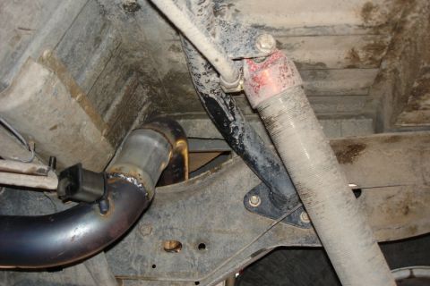 1987 Ford Bronco - Close-up of vehicle's undercarriage, focusing on the exhaust system and a shock absorber.