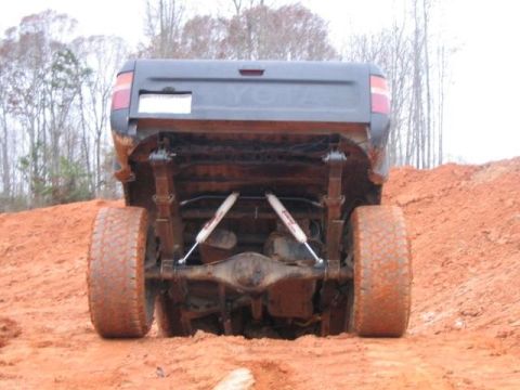 1986 Ford F-150 - Toyota truck's rear axle and suspension are visible as it is stuck in the mud.