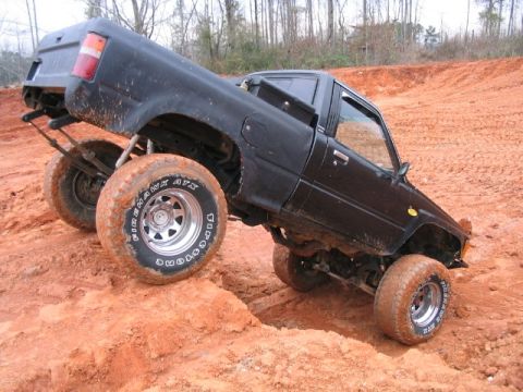 1986 Ford F-150 - This heavily modified pickup truck navigates a challenging off-road course with large, aggressive tires.