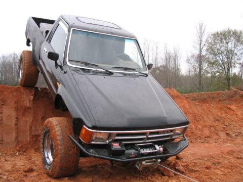 1986 Ford F-150 - A black Toyota pickup truck navigates a steep dirt incline, its off-road capabilities.