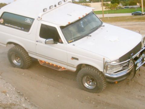1995 Ford Bronco - This 1995 Ford Bronco features off-road tires, a brush guard, and illuminated side steps, suggesting it's equipped for terrain.