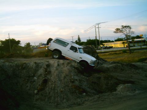 1995 Ford Bronco - White 1995 Ford Bronco is shown navigating a steep dirt incline.